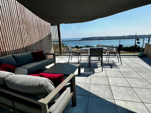 un patio avec un canapé, une table et des chaises dans l'établissement Appartement standing vue mer imprenable, à Brest