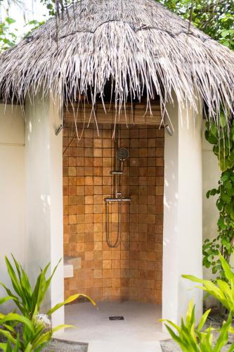 a shower in a straw hut with a thatched roof at Constance Halaveli in Hangnaameedhoo