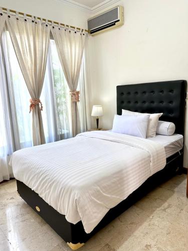 a bedroom with a large bed with white sheets and windows at Turtledove Guesthouse in Kerobokan