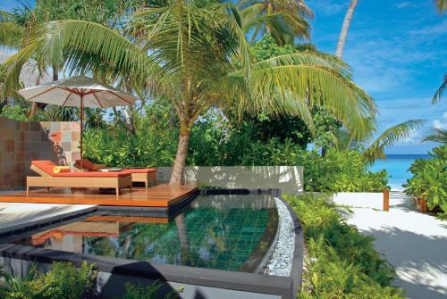 a swimming pool with a chair and an umbrella next to a resort at Constance Halaveli in Hangnaameedhoo