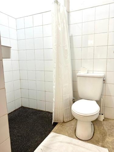 a white bathroom with a toilet and a shower at Turtledove Guesthouse in Kerobokan