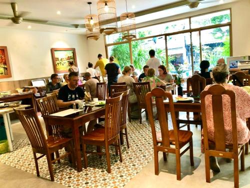 een groep mensen die aan tafels in een restaurant zitten bij De Vivre Hoi An Hotel in Hội An