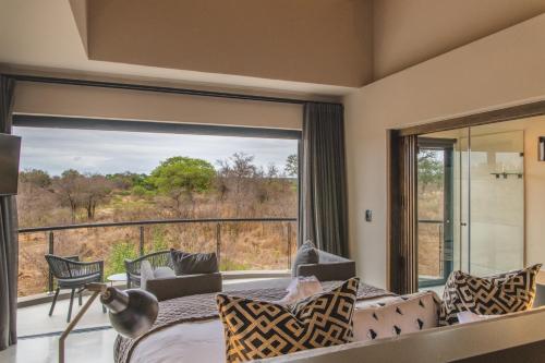 a bedroom with a large window and a bed and a couch at Elephant Point in Skukuza