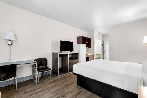 a white bedroom with a bed and a desk and chairs at Suburban Studios Chattanooga Northeast - Ooltewah in Chattanooga