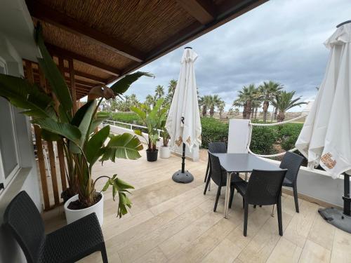 a patio with a table and chairs and a white umbrella at Pensión La Ola in Grao de Castellón