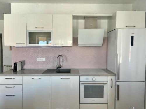 a white kitchen with a sink and a refrigerator at Apartments Keko in Primošten