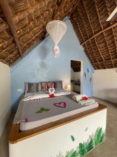 a bedroom with a bed in a blue wall at Kokopelli Bungalows in Nungwi