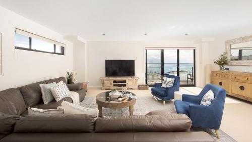 a living room with a couch and chairs and a television at Bay Vista Penthouse - Heart of Nelson Bay in Nelson Bay