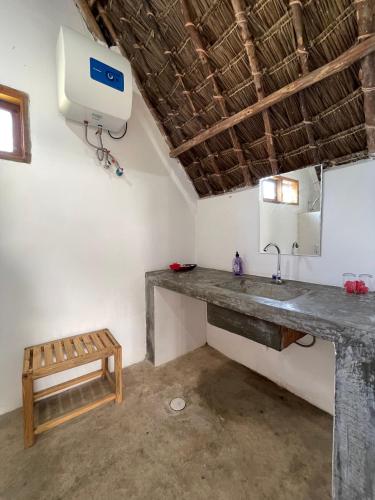 a bathroom with a sink and a bench in a room at Kokopelli Bungalows in Nungwi