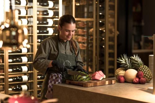 ミデルブルフにあるCityhotel Woodのエプロンを着た女性がカウンターで果物を切っている