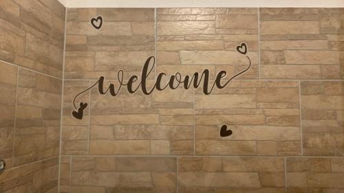 a welcome sign on a tiled bathroom floor with hearts at Toscan Panzió in Gyál