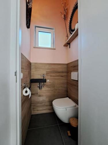 a bathroom with a toilet and a sink and a window at Have a nice stay! - Vakantiehuis Buitenplaats in Noordwijkerhout
