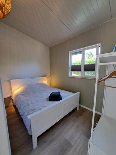 a bedroom with a white bed and a window at Have a nice stay! - Vakantiehuis Buitenplaats in Noordwijkerhout