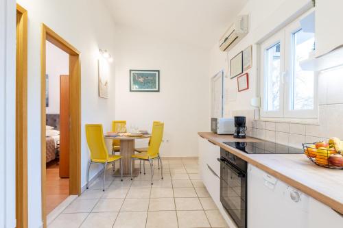 a kitchen and dining room with a table and yellow chairs at House Runjic with pool, large garden and playground in Prgomet