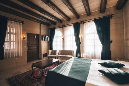 a bedroom with a bed and a chair and windows at Lagania In Cave in Urgup
