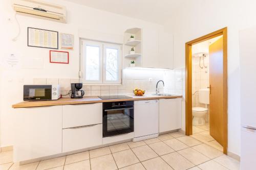 a kitchen with white cabinets and a sink at House Runjic with pool, large garden and playground in Prgomet