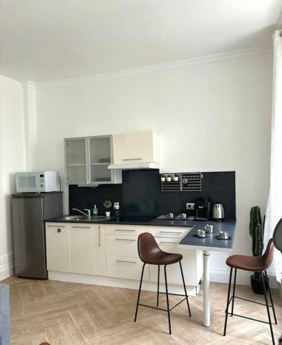 une cuisine avec des armoires blanches et une table et des chaises dans l'établissement Studio Châtivesle, à Reims