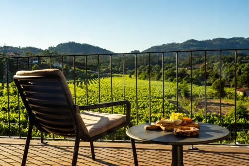 a chair and a table with a plate of food on a balcony at Quinta de Cypriano - Wine & Nature in Ponte da Barca