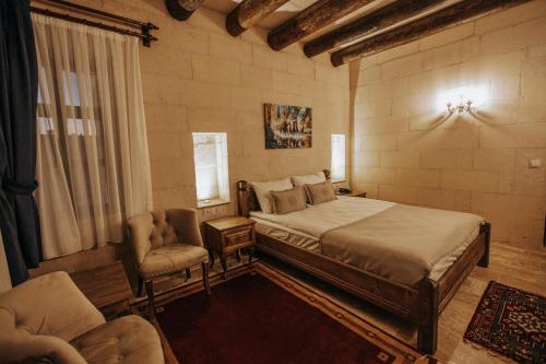 a bedroom with a large bed and two chairs at Lagania In Cave in Urgup