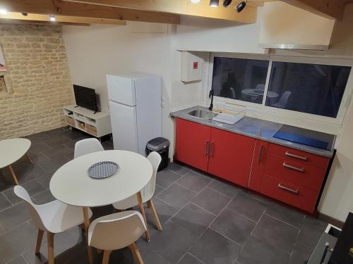 une cuisine avec des placards rouges, une table blanche et des chaises dans l'établissement Maison de ville, à Niort
