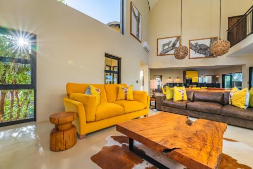 a living room with a yellow couch and a table at Elephant Point in Skukuza