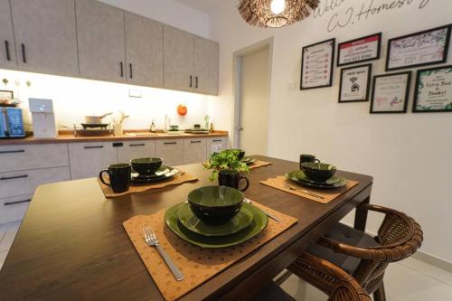 a kitchen with a wooden table with green dishes on it at Horizon Ipoh 8Pax 3R2B - Tropical Bali Retreat in Ipoh