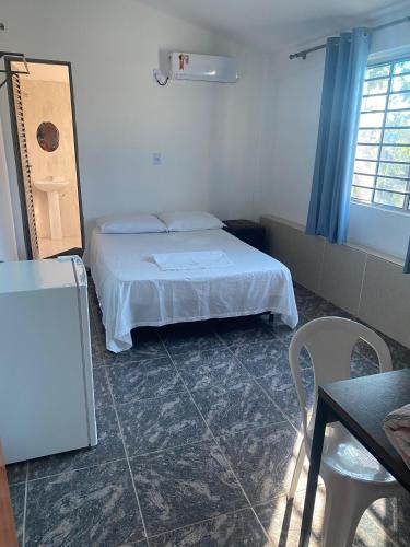 a bedroom with a bed and a table and a chair at Hotel Pousada Do Sol II in Aragarças