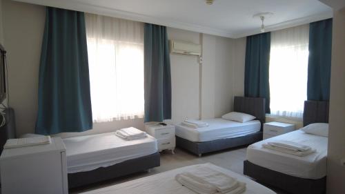 a room with two beds and two windows at Odak Pansiyon in Canakkale