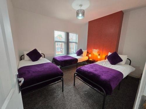 a room with two beds with purple pillows at The Grand four bed getaway- Sleeps 9-free on street parking in Birmingham