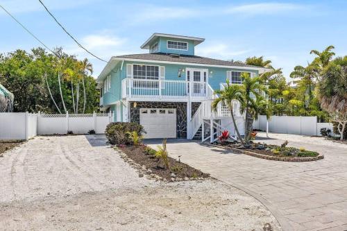 a blue house with a white fence and a driveway at Isla Living, 3 Bed, Canal, Pool in Anna Maria