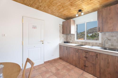a kitchen with wooden cabinets and a sink and a window at Vivienda vacacional La Era I in Vallehermoso