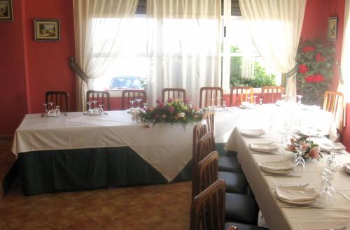 a dining room with a long table with flowers on it at Hotel Restaurante Campomar in Cartagena