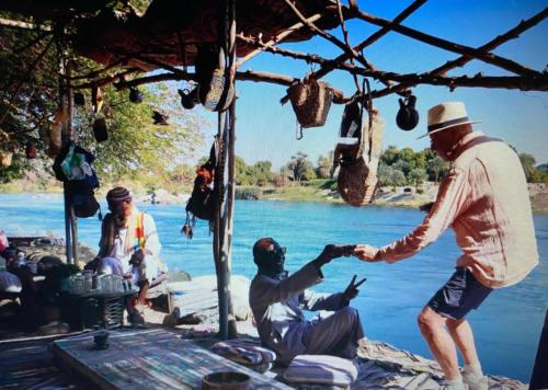 a man shaking another mans hand next to a river at Nubian Life Nile View in Aswan
