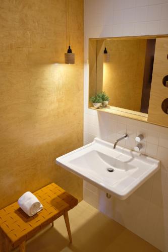 a bathroom with a white sink and a wooden bench at Casa das Penhas Douradas - Burel Expedition Hotel in Manteigas
