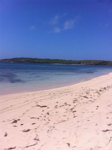 a beach with footprints in the sand and water at Villa Entre Ciel et Mer in Sainte-Anne