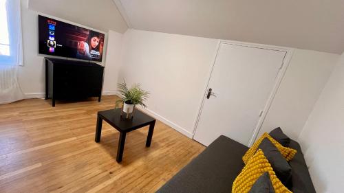 a living room with a couch and a table with a tv at Europole 2 Gare de Grenoble & centre ville in Grenoble