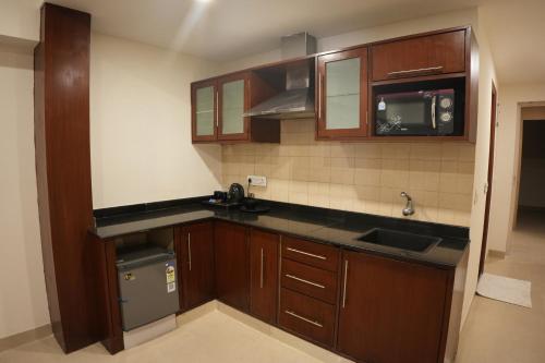 an empty kitchen with wooden cabinets and a sink at AK Castle Suites in Bengaluru
