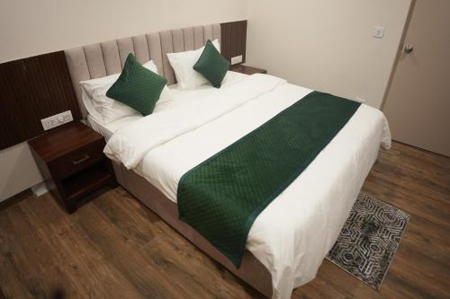 a large bed with green and white sheets and pillows at AK Castle Suites in Bengaluru