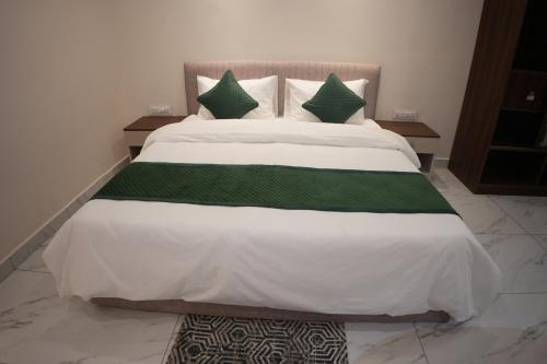 a large bed with green and white sheets and pillows at AK Castle Suites in Bengaluru
