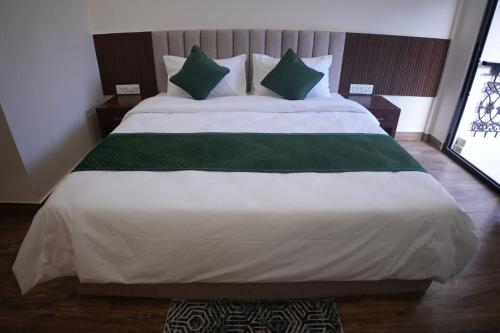 a large bed with green and white sheets and pillows at AK Castle Suites in Bengaluru