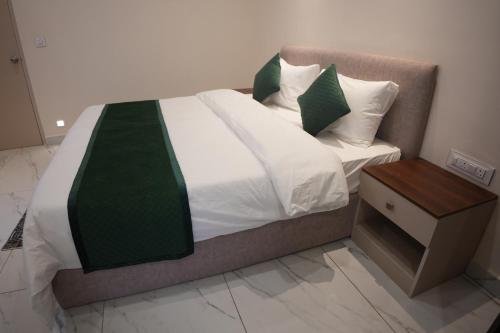 a bed with green and white sheets and a night stand at AK Castle Suites in Bengaluru