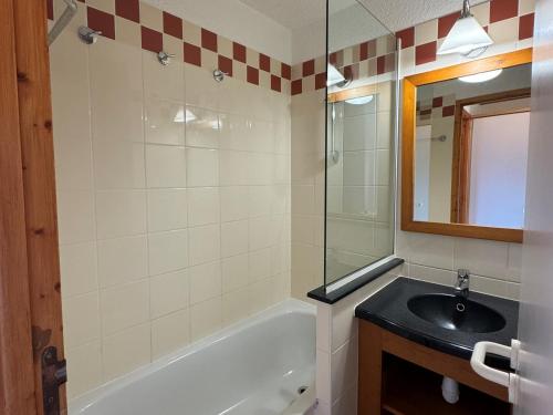 une salle de bain avec un lavabo, une baignoire et un miroir dans l'établissement Studio cabine au pied des pistes avec balcon et casier à skis - FR-1-181-2209, à La Plagne Tarentaise