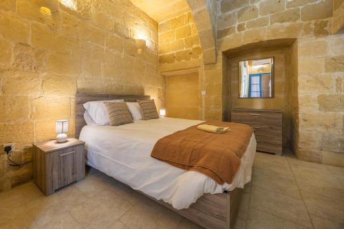 a bedroom with a large bed in a stone wall at Room 6 - Family room x 3 by Solea in Għarb