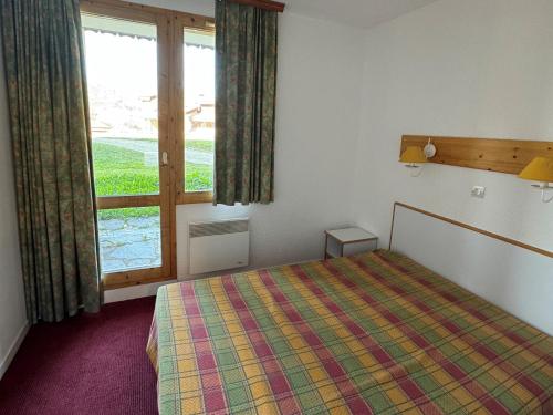 une chambre avec un lit et une grande fenêtre dans l'établissement Appartement au pied des pistes avec WIFI et animaux admis - FR-1-181-2247, à La Plagne Tarentaise