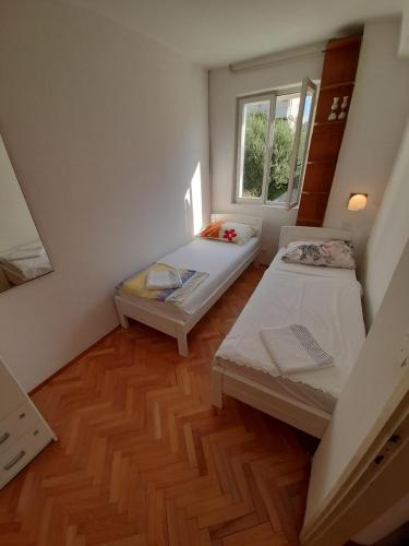 a small room with two beds and a window at Apartmants Emy in Novalja