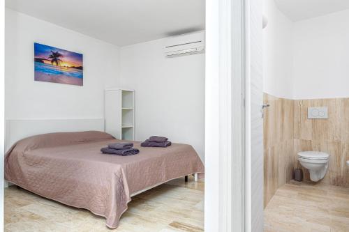 a white bedroom with a bed and a toilet at Villa Smeraldina in Olbia
