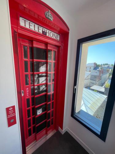 a red phone booth in a room with a window at The Originals Boutique, Hôtel Le Londres, Saumur in Saumur