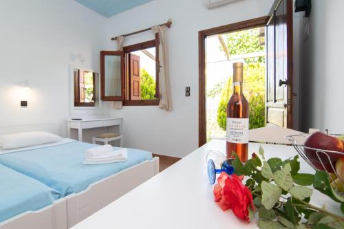 a room with a bed and a bottle of wine at Giannakos Apartments in Ydroússa