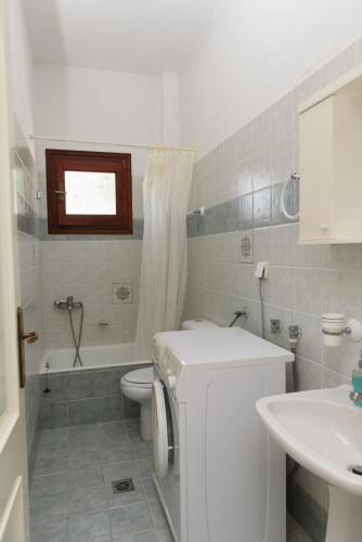 a bathroom with a sink and a toilet and a tub at Giannakos Apartments in Ydroússa