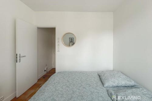 une chambre avec un lit et un miroir au mur dans l'établissement Flexliving - room - Augereau, à Paris